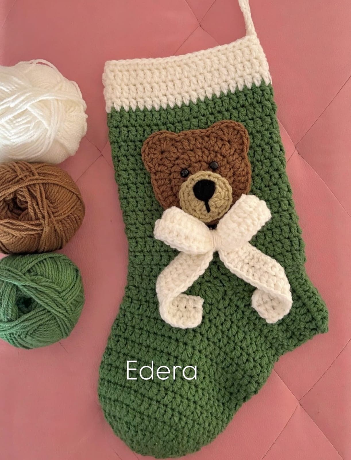 Green crochet stocking with a teddy bear and a white bow