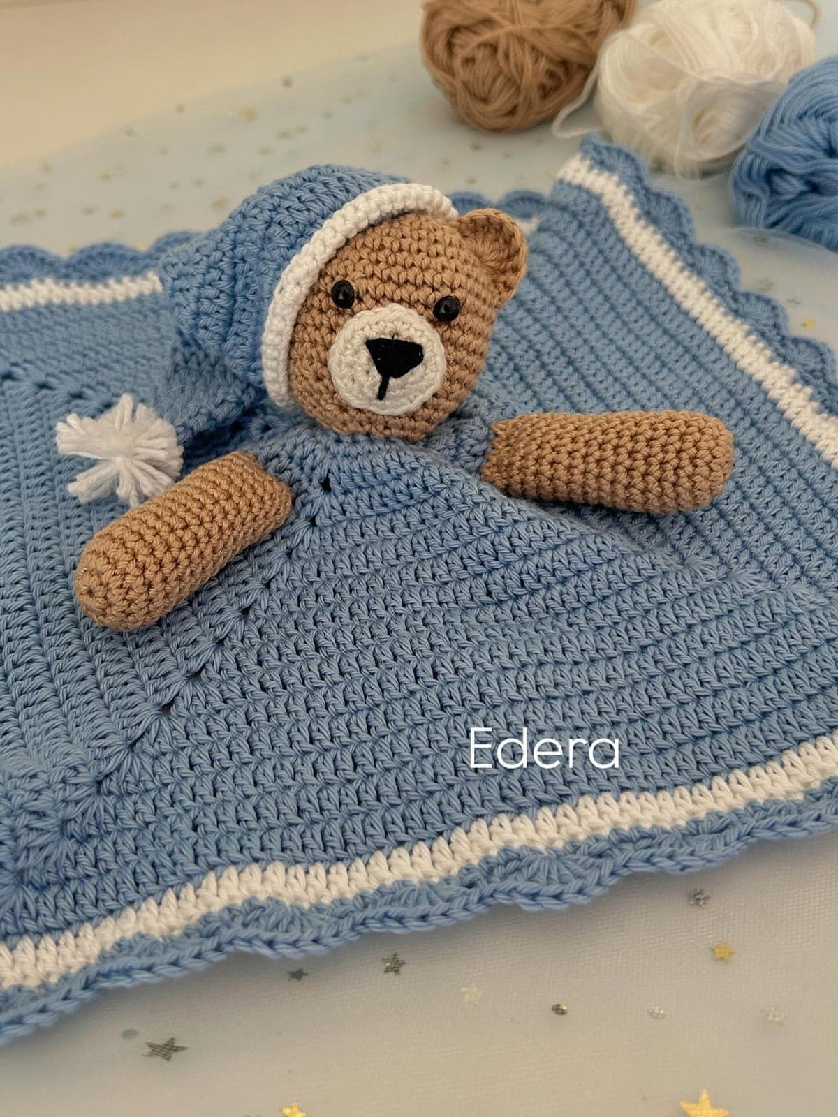Blue crochet lovey with an amigurumi teddy bear wearing a little hat